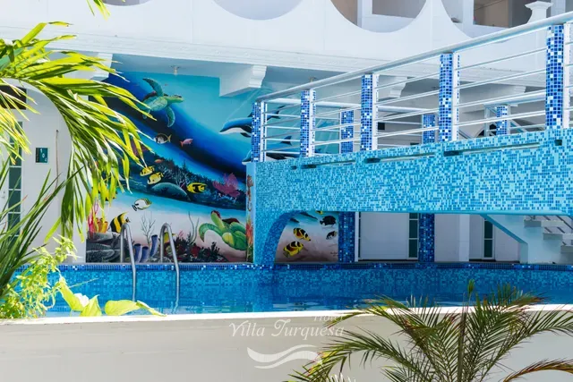 Alberca y mural marino entre palmeras · Hotel Villa Turquesa