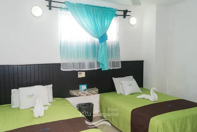 Dos camas matrimoniales con colcha verde · Hotel Villa Turquesa