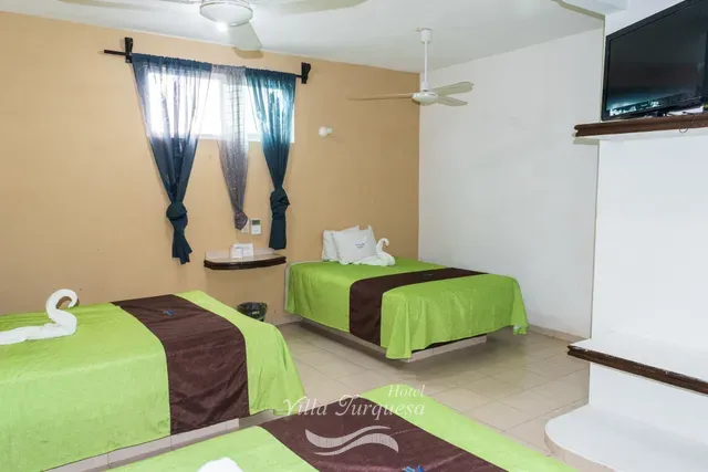 Televisión y ventilador de techo frente a las camas · Hotel Villa Turquesa